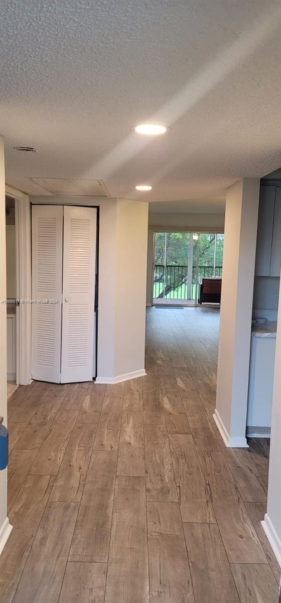 hall with a textured ceiling and hardwood / wood-style flooring