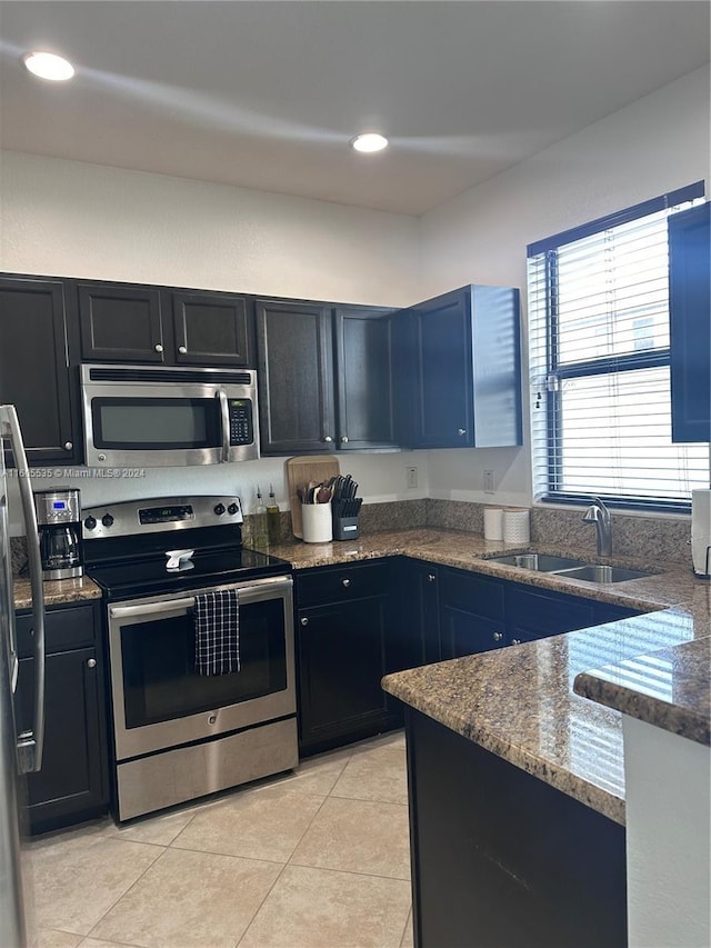 kitchen with dark stone countertops, light tile patterned flooring, sink, and stainless steel appliances