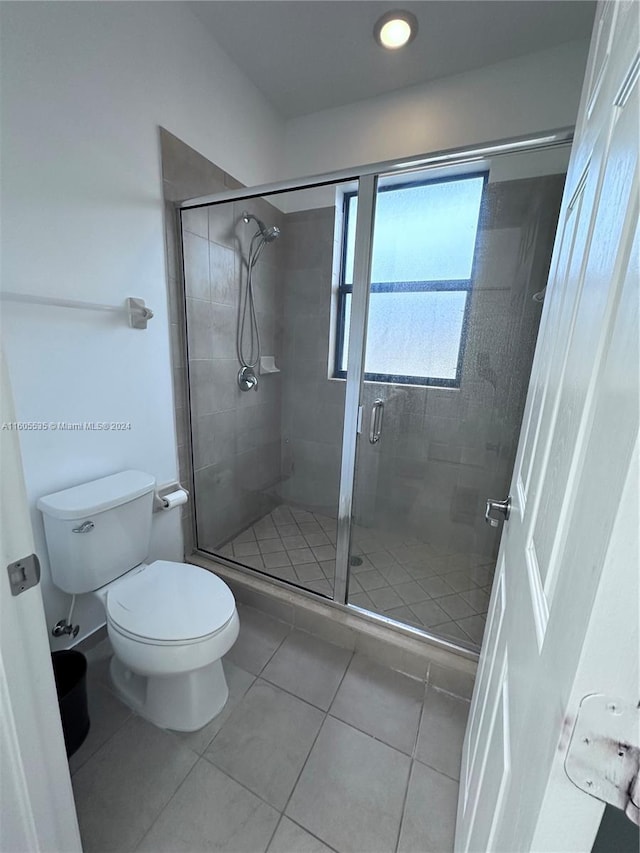 bathroom with an enclosed shower, toilet, and tile patterned floors