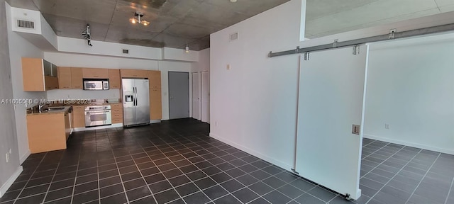 kitchen featuring a high ceiling, appliances with stainless steel finishes, sink, and dark tile patterned flooring