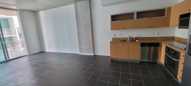 kitchen featuring sink, light brown cabinets, dark tile patterned floors, and appliances with stainless steel finishes