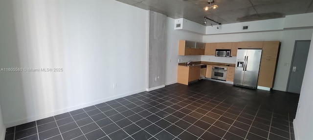 kitchen featuring appliances with stainless steel finishes, rail lighting, sink, a high ceiling, and light brown cabinets