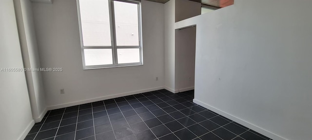 unfurnished room featuring dark tile patterned flooring