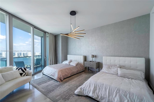 bedroom featuring access to exterior, a chandelier, and a wall of windows