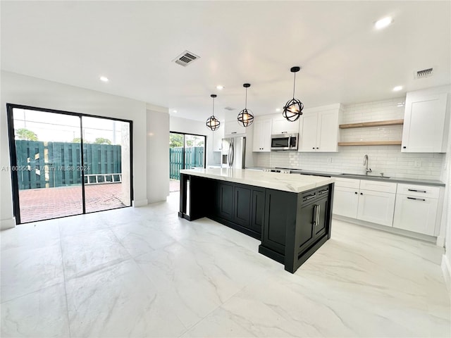 kitchen with sink, hanging light fixtures, a kitchen island, white cabinets, and appliances with stainless steel finishes