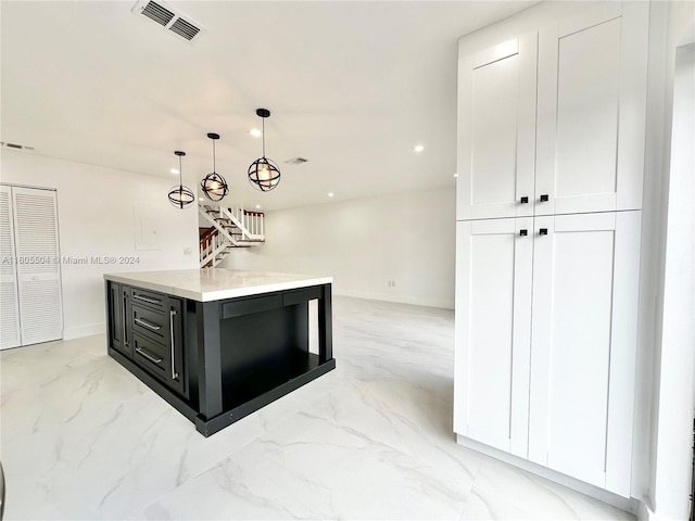 kitchen featuring pendant lighting, a kitchen island, and white cabinets