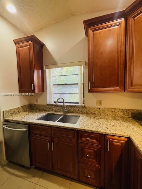 kitchen featuring dishwasher, vaulted ceiling, light stone counters, light tile floors, and sink