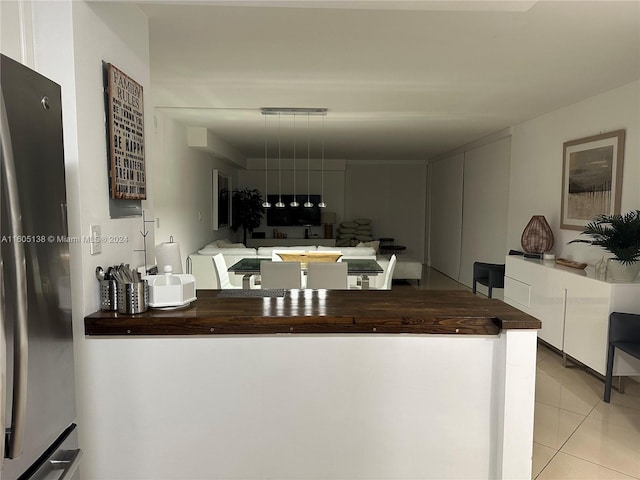 kitchen featuring light tile patterned floors, wooden counters, and freestanding refrigerator