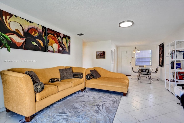 living room featuring an inviting chandelier, a textured ceiling, and tile patterned floors