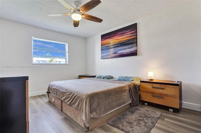 bedroom with wood-type flooring, ceiling fan, and a textured ceiling