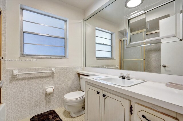 bathroom featuring vanity, tile walls, a shower with shower door, and toilet