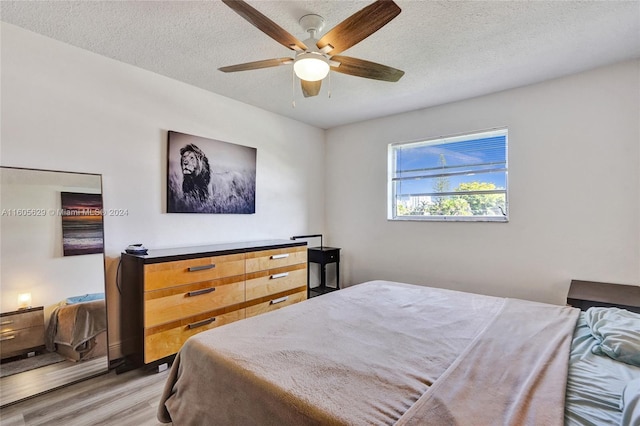 bedroom with light hardwood / wood-style flooring, ceiling fan, and a textured ceiling