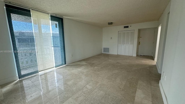 empty room with floor to ceiling windows and a textured ceiling