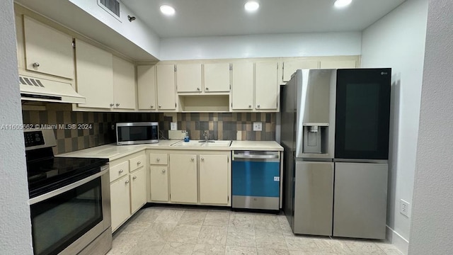 kitchen featuring decorative backsplash, stainless steel appliances, cream cabinets, and range hood