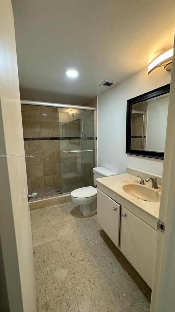 bathroom featuring walk in shower, vanity, and toilet