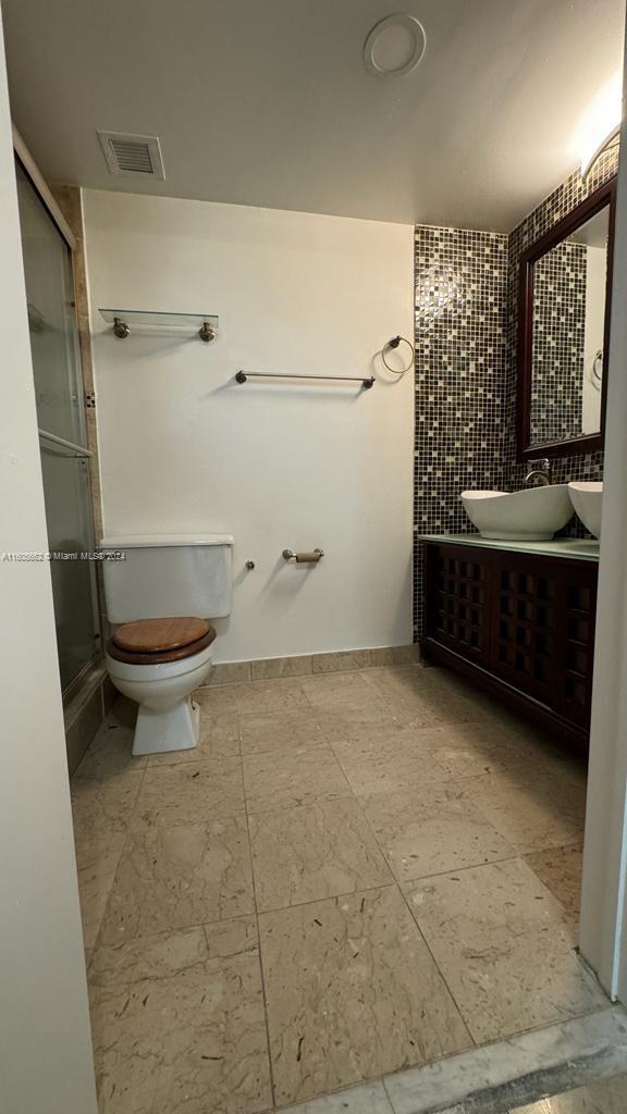 bathroom featuring a shower with door, toilet, and vanity