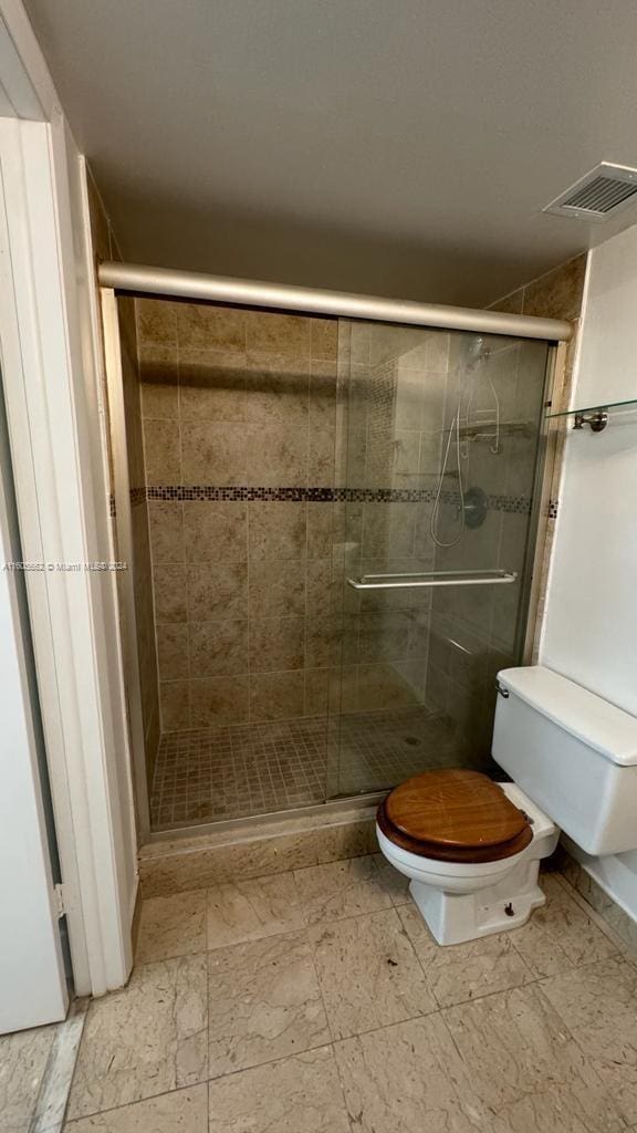 bathroom with toilet and a shower with shower door