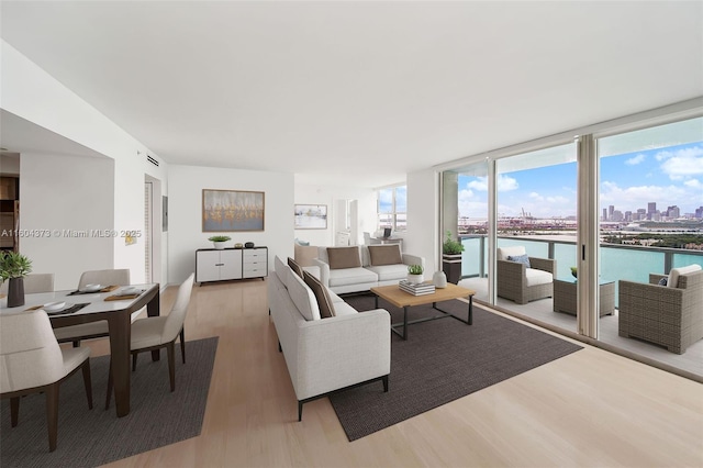 living room featuring light wood-type flooring, a wall of windows, and a water view