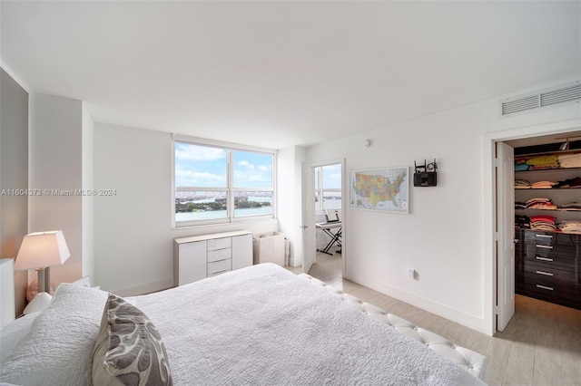 bedroom with a water view, radiator heating unit, and light hardwood / wood-style flooring