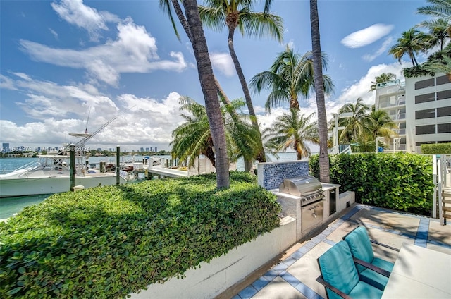 view of patio with an outdoor kitchen, a water view, and a grill