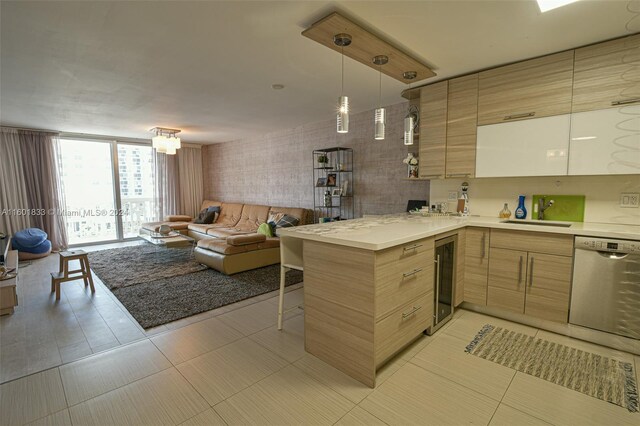 kitchen with light brown cabinetry, kitchen peninsula, light tile floors, and stainless steel dishwasher