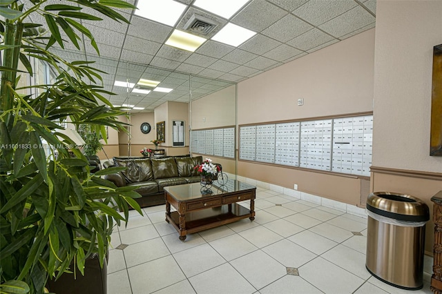 living room with a mail area, tile floors, and a paneled ceiling