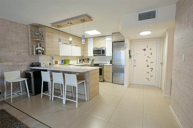 kitchen with hanging light fixtures, a kitchen breakfast bar, stainless steel appliances, kitchen peninsula, and sink