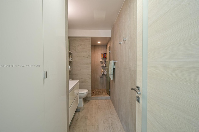 bathroom featuring a shower, vanity, toilet, and tile walls