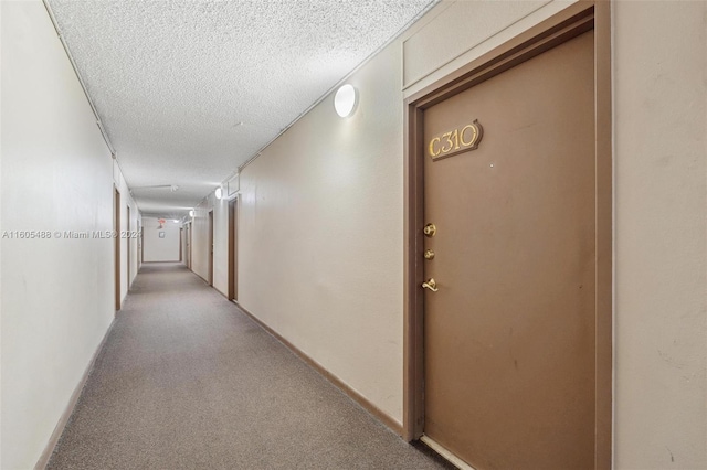 corridor with a textured ceiling and carpet floors