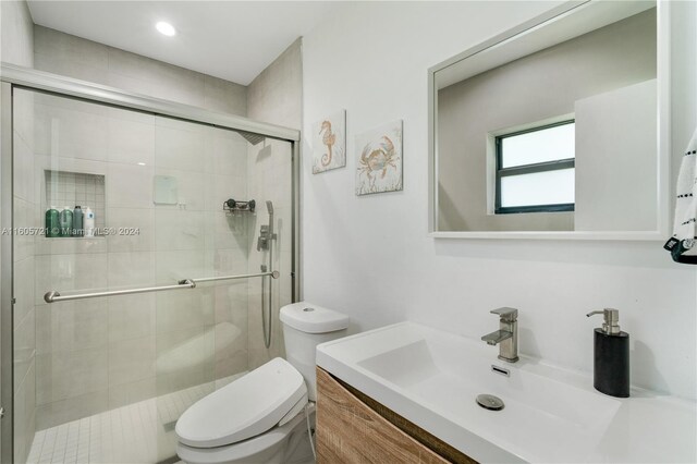 bathroom with vanity, toilet, and a shower with shower door