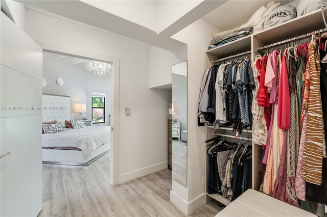 walk in closet featuring light hardwood / wood-style flooring and an inviting chandelier