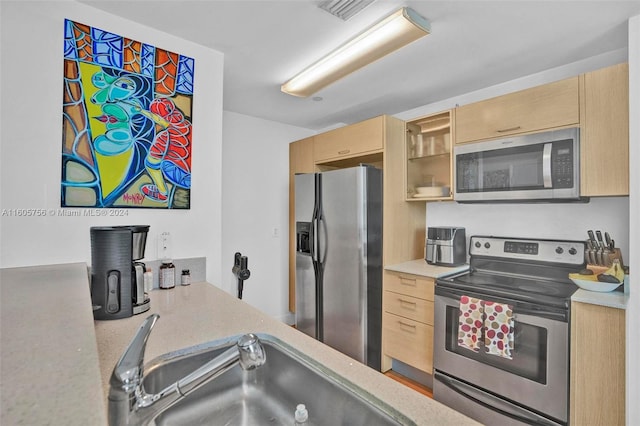 kitchen featuring stainless steel appliances, light brown cabinets, and sink