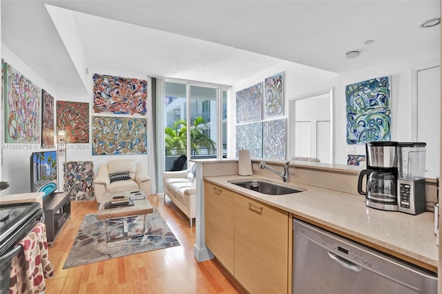 kitchen with sink, dishwasher, light brown cabinetry, light stone countertops, and light hardwood / wood-style floors