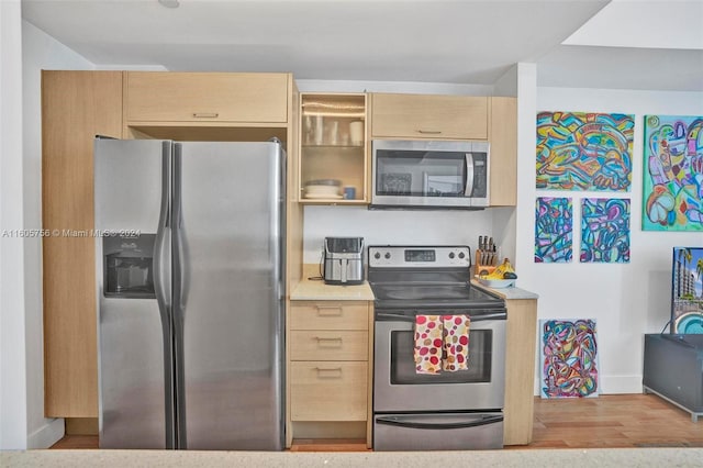 kitchen featuring stainless steel appliances, light brown cabinetry, and light wood-type flooring