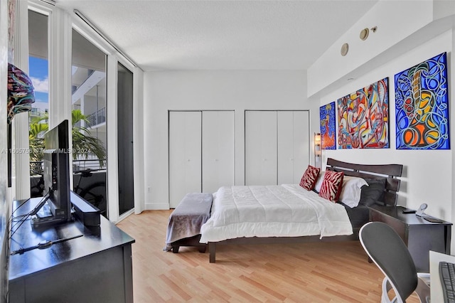 bedroom featuring two closets, a textured ceiling, and hardwood / wood-style flooring