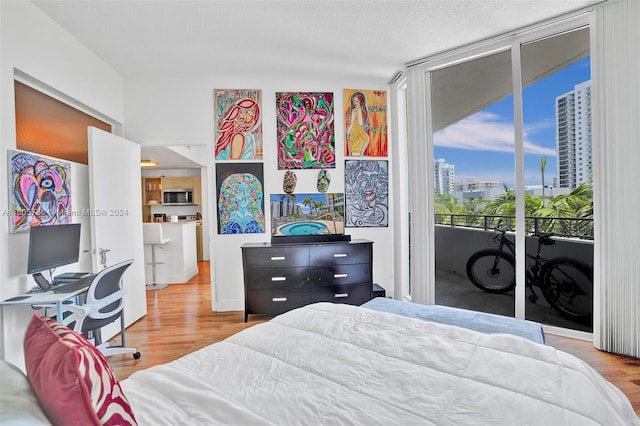 bedroom with wood-type flooring, a textured ceiling, and access to exterior