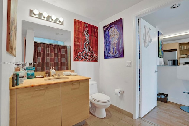 bathroom with wood-type flooring, vanity, and toilet