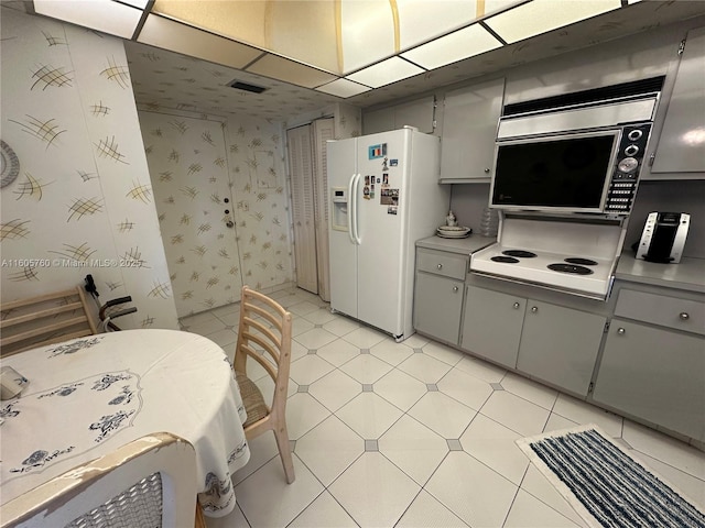 kitchen with white refrigerator with ice dispenser, stovetop, and gray cabinetry