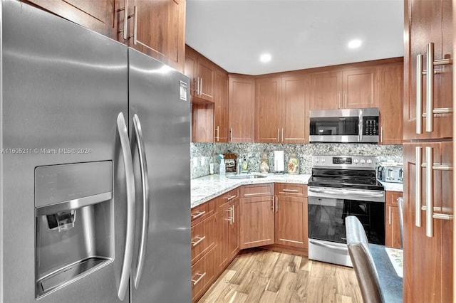 kitchen featuring stainless steel appliances, decorative backsplash, light hardwood / wood-style floors, and sink