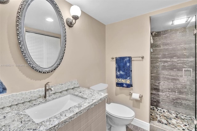 bathroom featuring toilet, vanity, and a tile shower