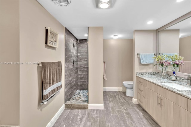 bathroom with toilet, vanity, and a tile shower