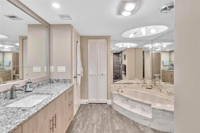 bathroom featuring toilet, tiled tub, hardwood / wood-style floors, and vanity