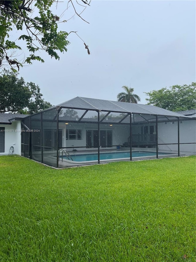 view of swimming pool with a lanai and a lawn