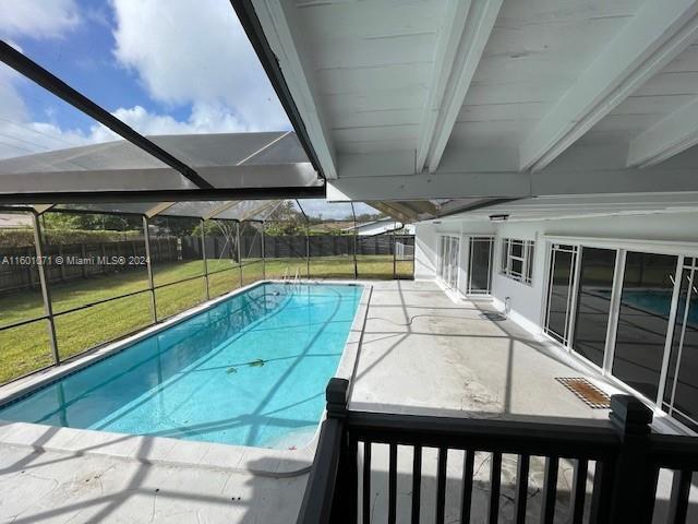 view of swimming pool with glass enclosure and a lawn