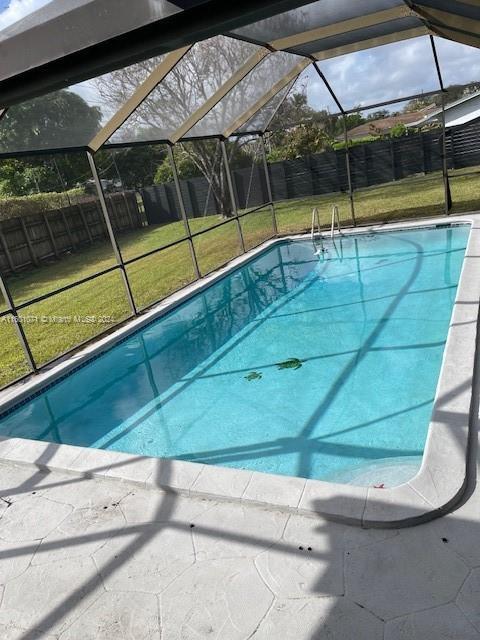 view of swimming pool with a yard and a lanai