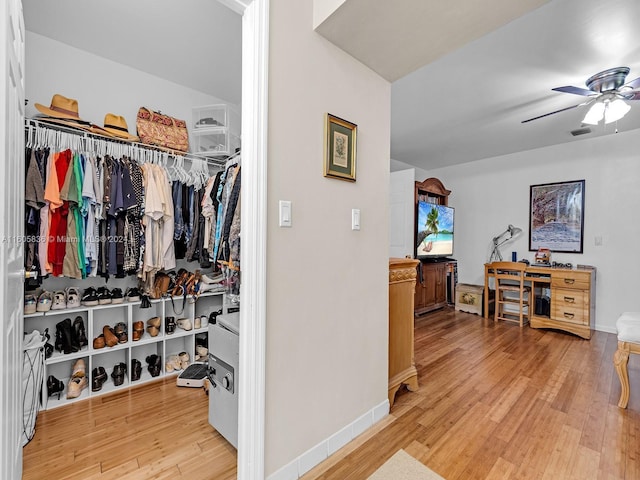 walk in closet featuring light hardwood / wood-style floors and ceiling fan