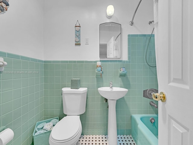 bathroom with tile walls, tile patterned flooring, toilet, and tiled shower / bath