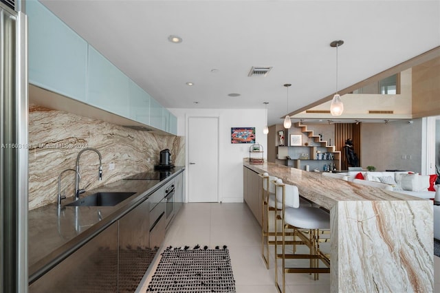 kitchen with sink, a kitchen breakfast bar, backsplash, kitchen peninsula, and black electric cooktop