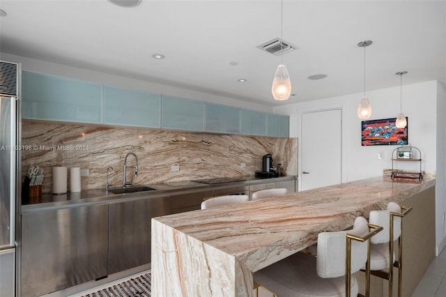 kitchen featuring decorative backsplash, a kitchen bar, kitchen peninsula, sink, and pendant lighting