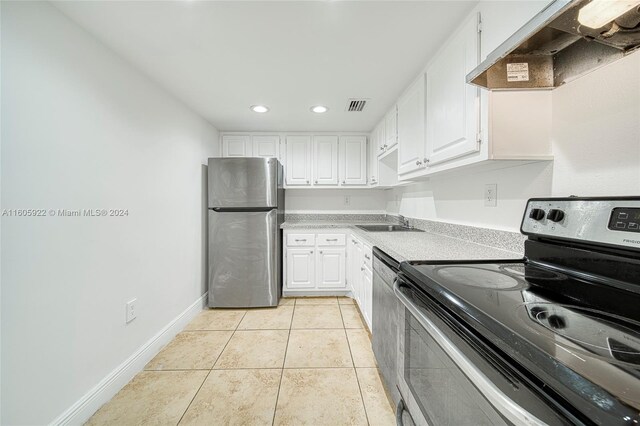 kitchen featuring light tile floors, wall chimney range hood, sink, white cabinetry, and appliances with stainless steel finishes